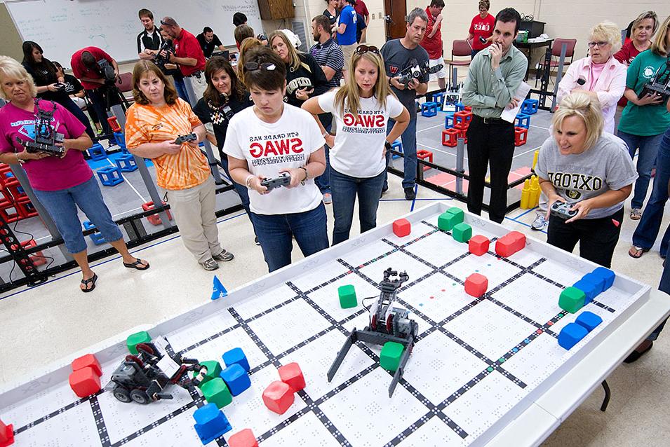 Teachers control robots with game controllers during an Inservice training.