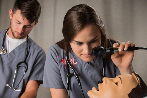 Nursing student examines simulation mannequin