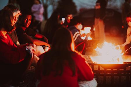 Students cooking S'mores at a fire
